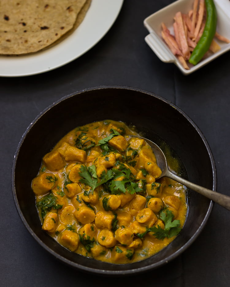 A close-up of the gattas being cooked in a rich, spicy gravy with a glossy finish
