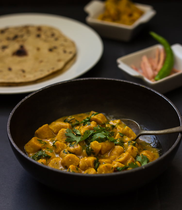 A spoonful of Gatte Ki Sabji being taken from the bowl, showcasing the texture of the gattas