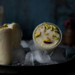 Traditional cone-shaped Malai Kulfi served on a plate with a sprinkle of cardamom powder