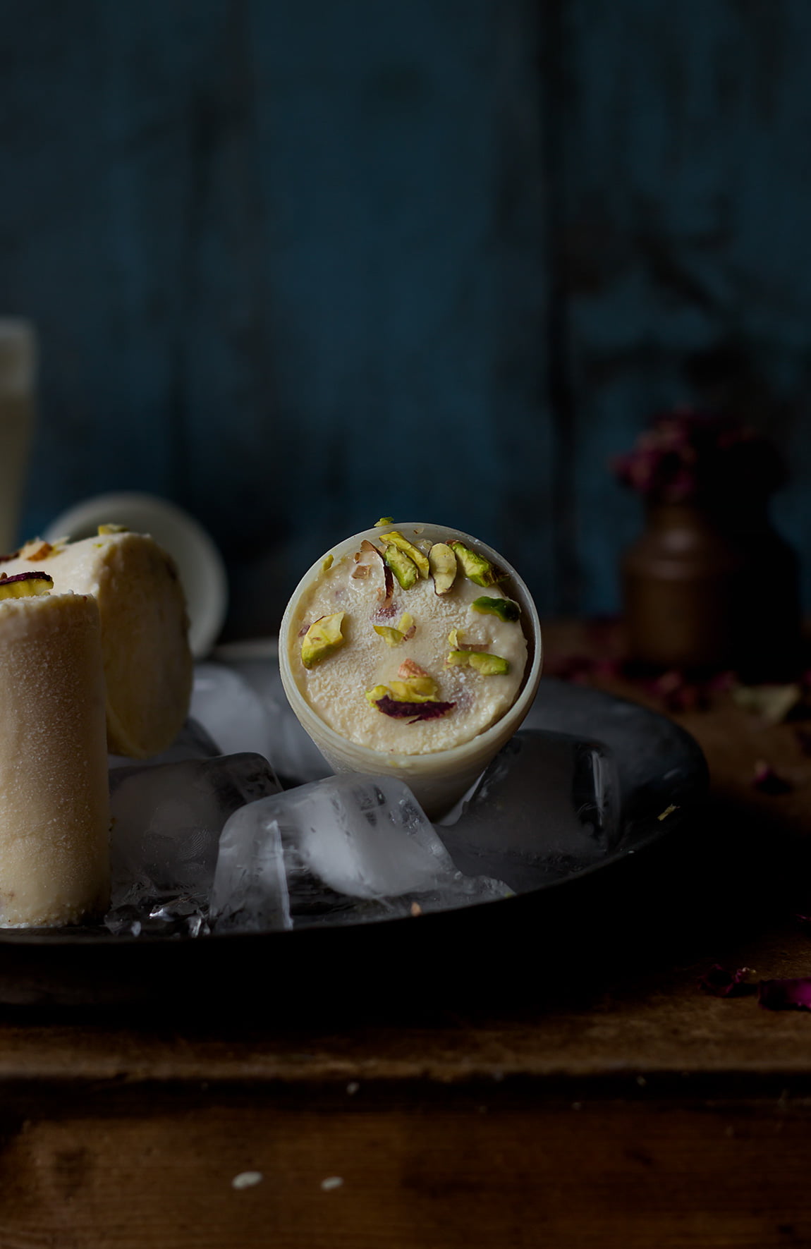 Traditional cone-shaped Malai Kulfi served on a plate with a sprinkle of cardamom powder