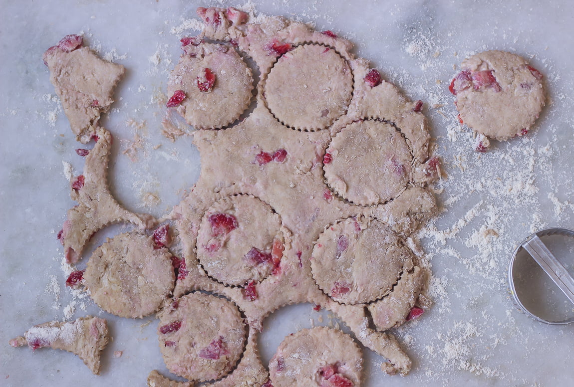 A round cutter cutting strawberry scone shapes from the dough