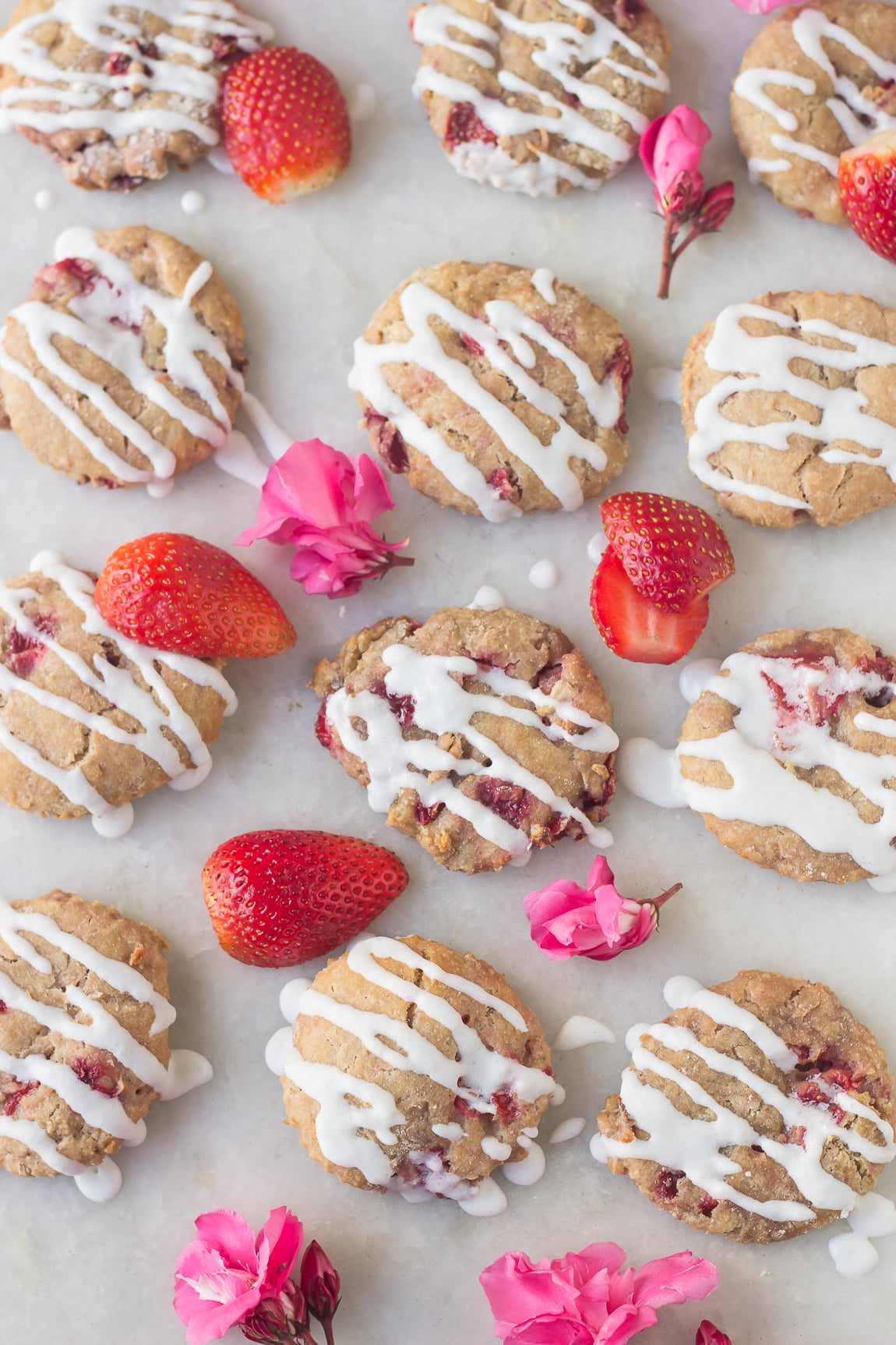 Drizzling glaze over warm strawberry scones on a cooling rack