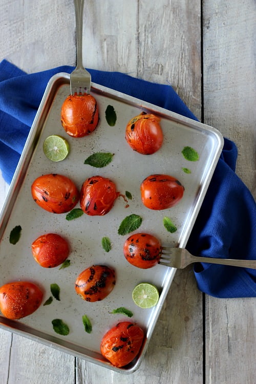 Top view of the blanched tomatoes in a tray with the slices of lemon