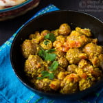 A delicious serving of Bengali Style Dry Dum Aloo (Bengali Aloo Dum) garnished with fresh coriander on a white plate
