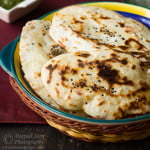 Homemade naan stacked neatly on a plate