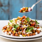 A spoonful of sprouted moong salad showing a mix of fresh vegetables and sprouts.