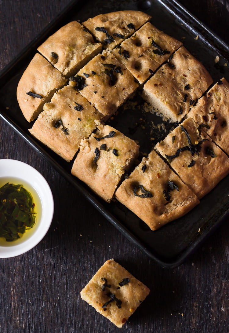 Close-up of freshly baked whole wheat basil focaccia bread cut into square shapes