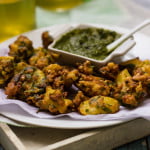 A plate of golden Aloo Bread Pakoris served with green chutney