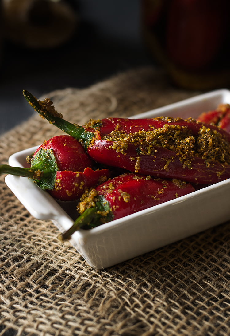 Whole Bharwan Lal Mirch ka Achar arranged on a plate, showcasing vibrant red chilies stuffed with spices