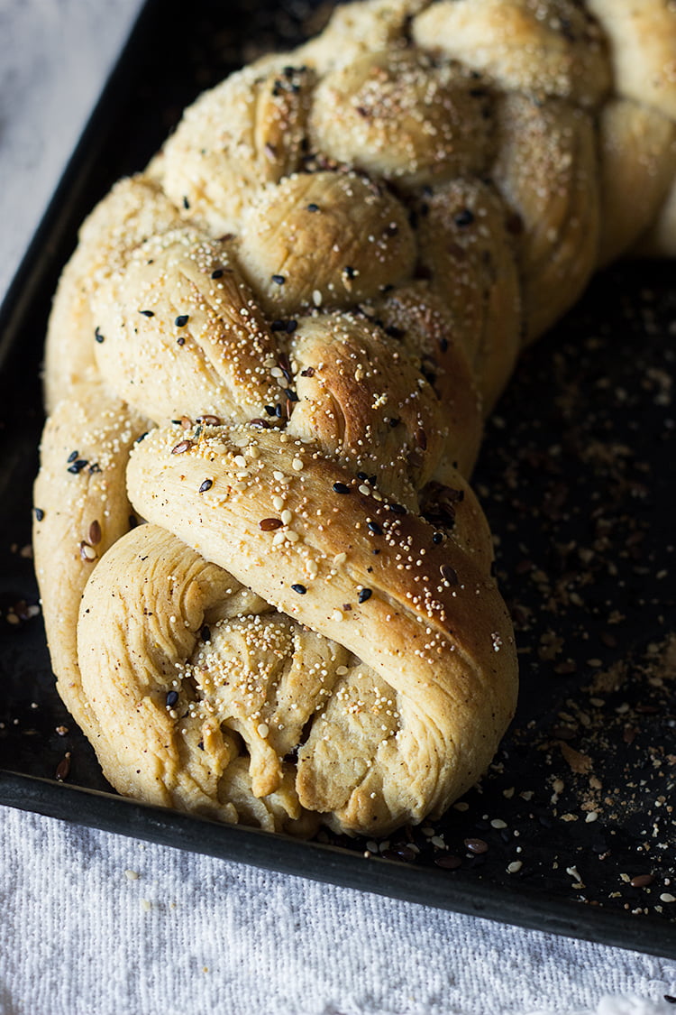 Close-up of freshly baked golden brown braided challah bread on a wooden board