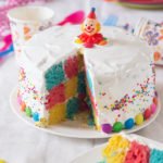 Whole Rainbow Checkerboard Cake topped with creamy white frosting