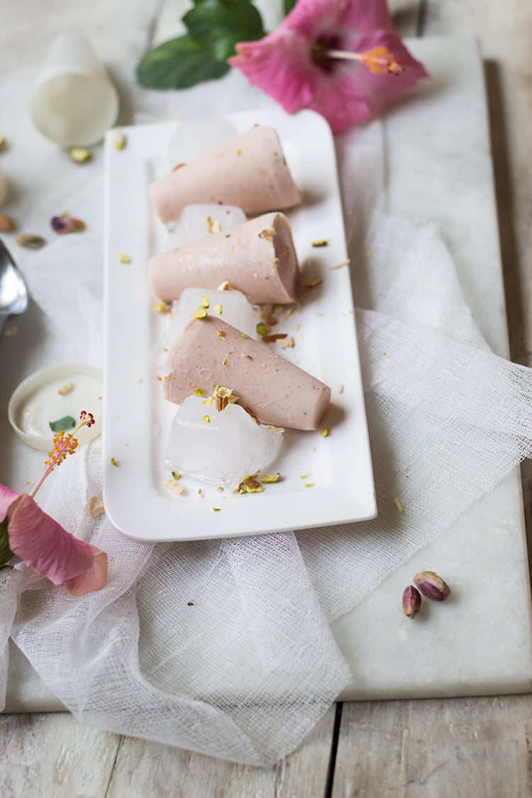 Strawberry Malai Kulfi garnished with crushed pistachios on a white plate