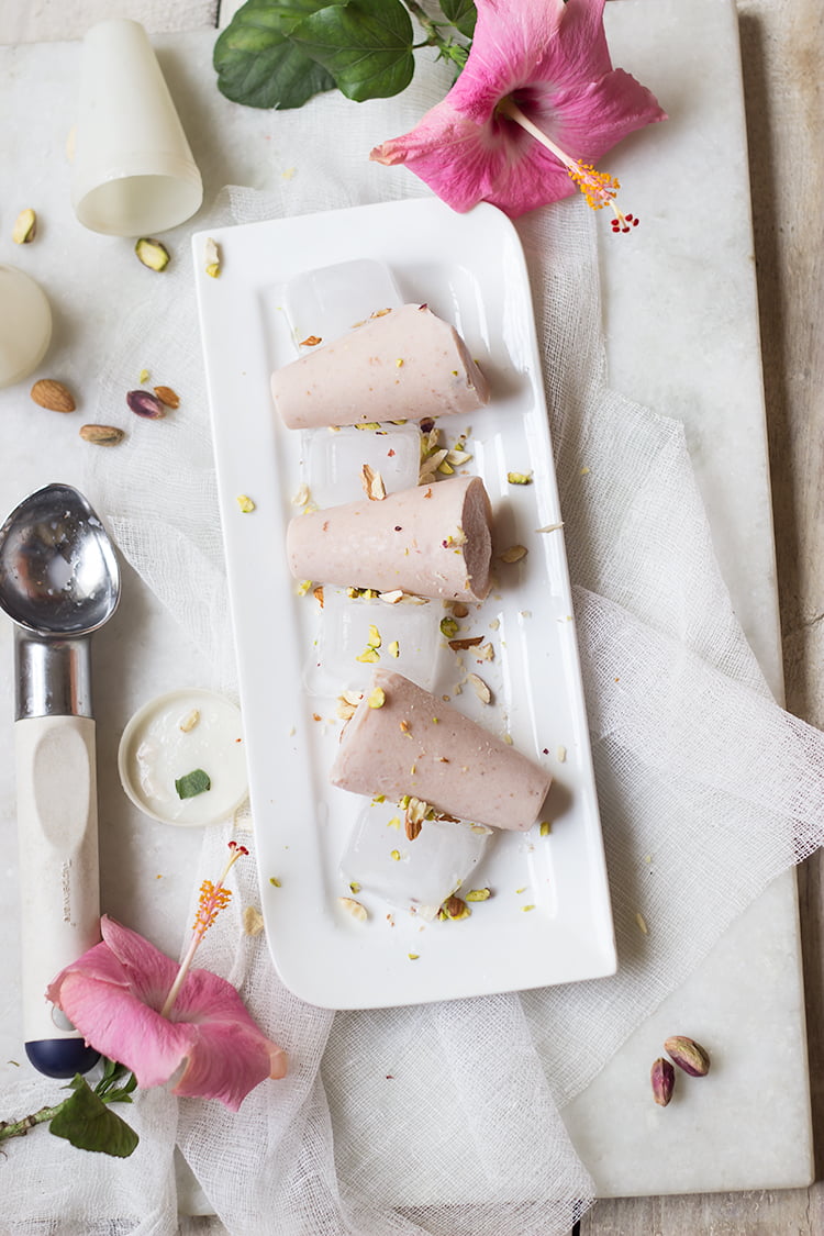 Freshly made Strawberry Malai Kulfi being unmolded from a metal kulfi mold