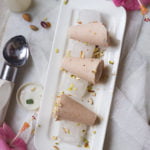 Strawberry Malai Kulfi garnished with crushed pistachios on a white plate