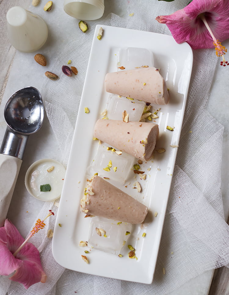 A close-up of a creamy Strawberry Malai Kulfi on a stick