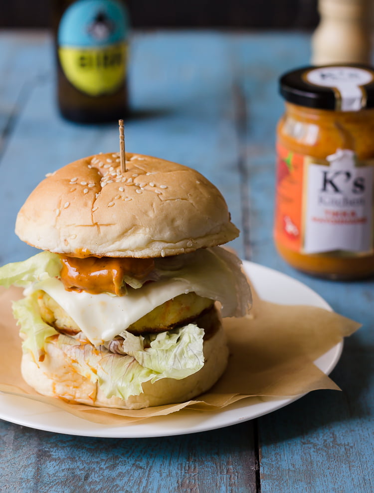 A cross-section view of a crispy paneer tikka burger showcasing the juicy paneer patty, fresh vegetables