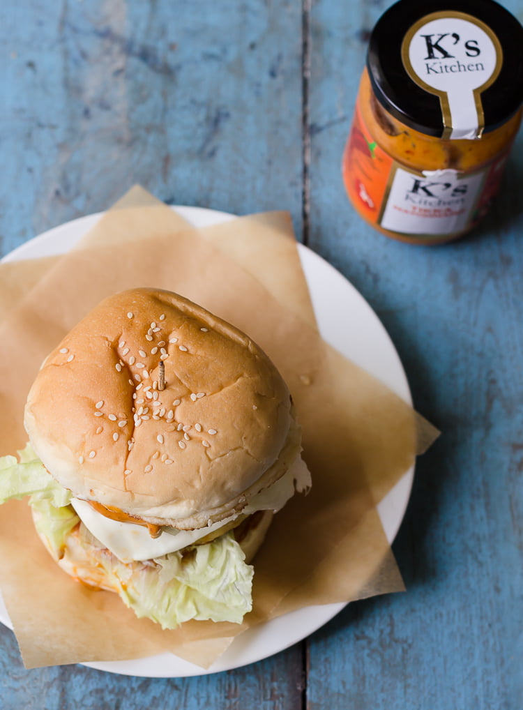 A beautifully plated crispy paneer tikka burger served on a plate
