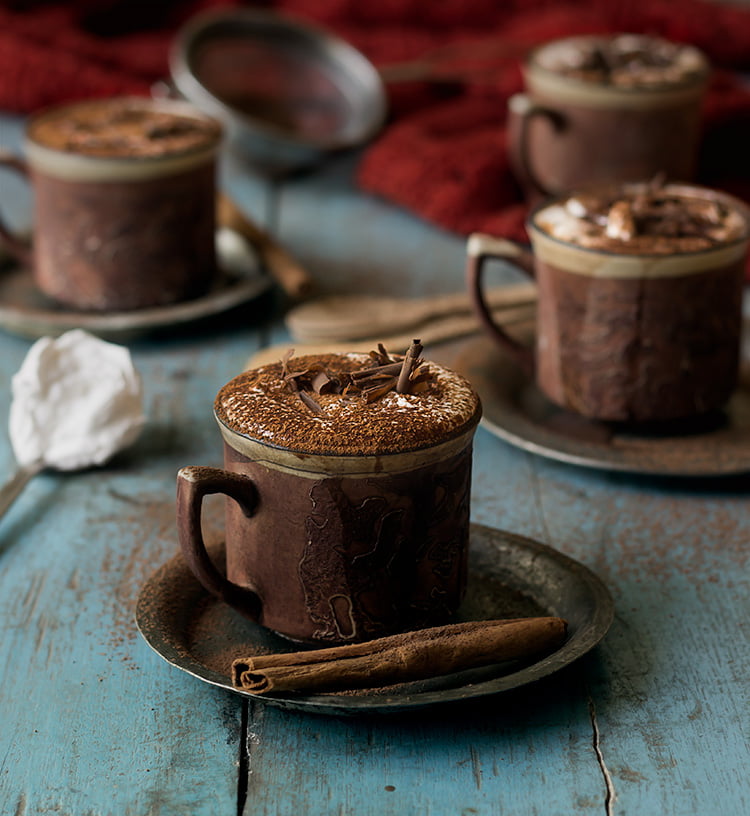 Top view of a mug of hot chocolate with a sprinkle of cinnamon and chocolate shavings