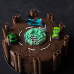 A fabulous race track cake with two toy car at the top