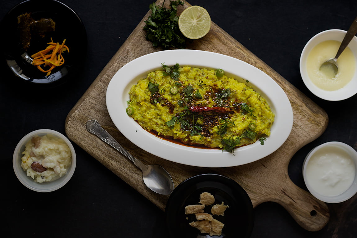 A plate full of Bajre Ki Khichdi garnished with fresh coriander and served with a side of yogurt