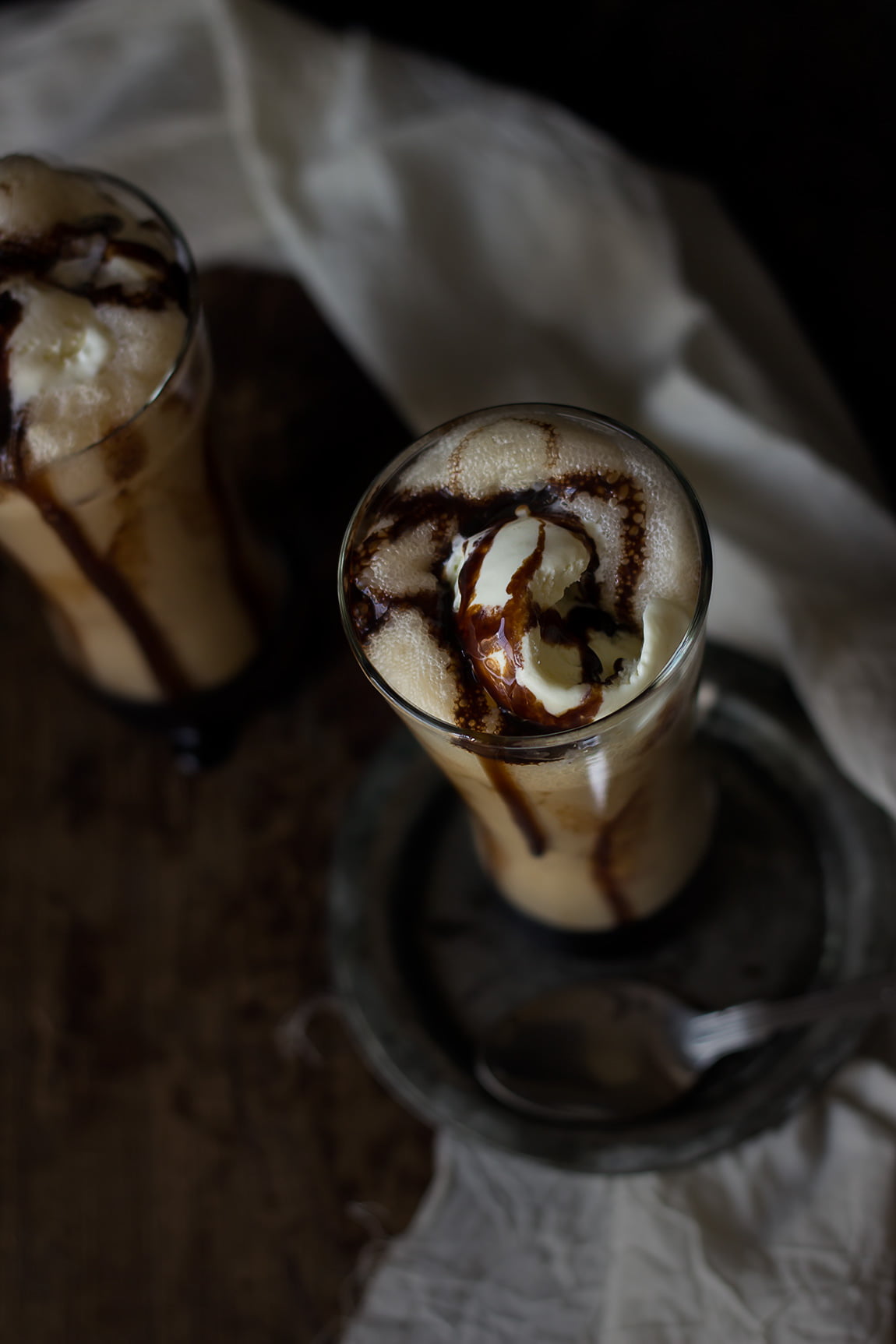 Close-up of an iced coffee frappe with a thick layer of whipped cream and chocolate syrup drizzling down the sides