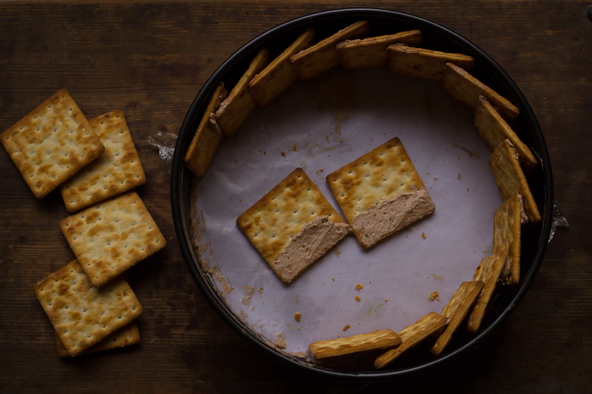 Breaking biscuits into small pieces in a baking tray for the chocolate biscuit cake