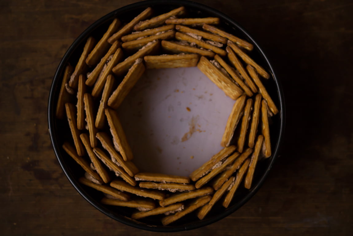 Ingredients for no-bake biscuit cake: chocolate bars, butter, and biscuits on a countertop