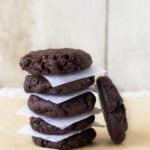 A stack of freshly baked double chocolate chip cookies on a cooling rack