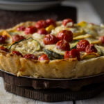 Serving Tomato Zucchini Tart on a white plate, ready to dig in