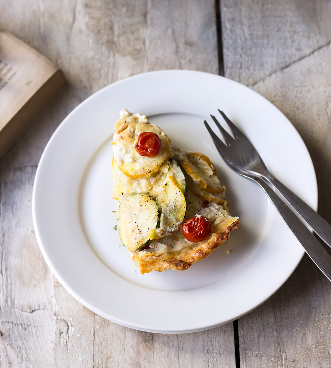 A slice of Tomato Zucchini Tart placed on a white plate