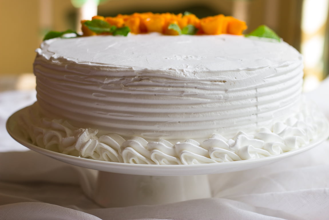 Overhead view of the whole eggless mango rose cake on a cake stand
