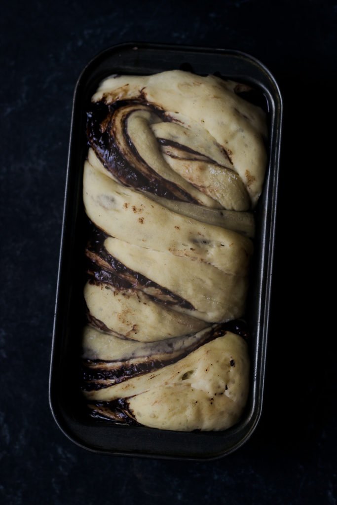 Chocolate Babka cooling on a wooden board, highlighting the braided chocolate layers