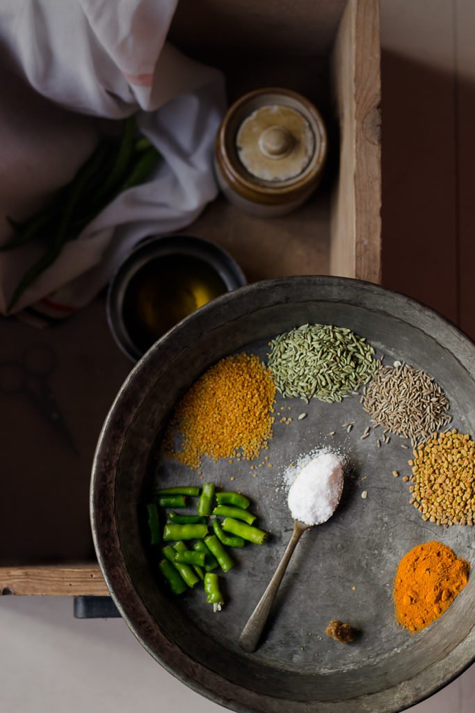 A plate filled with raw chillies and the spices to make hari mirch ka achar