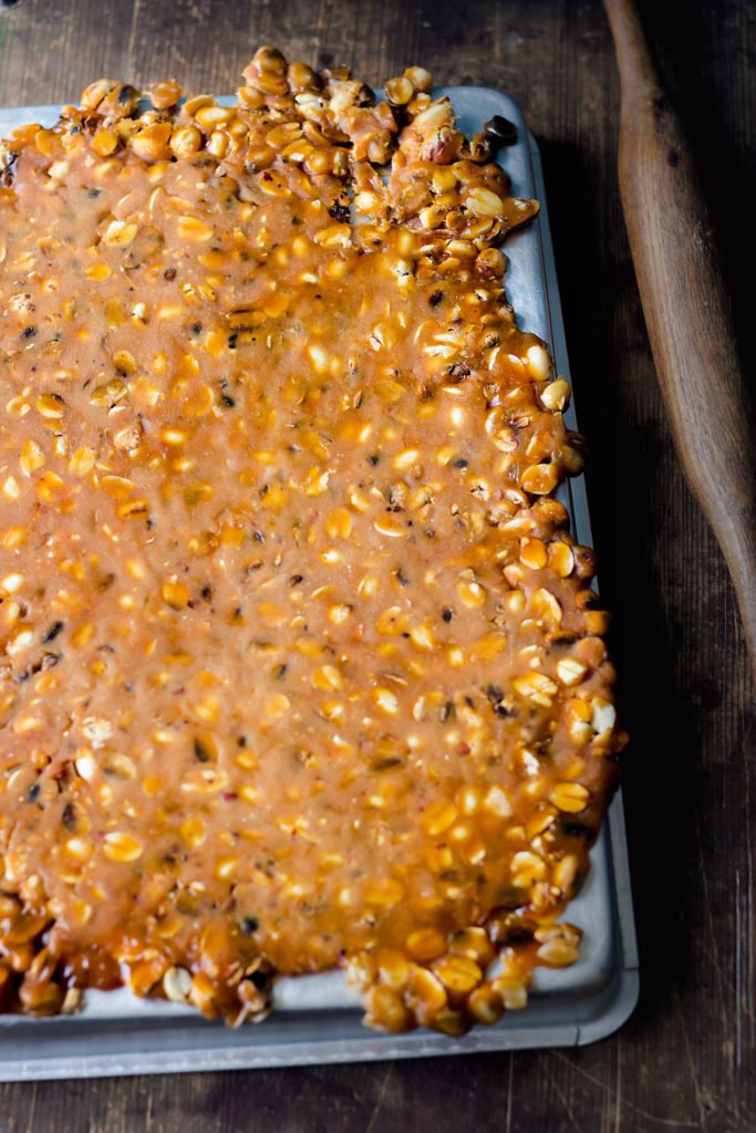 Spreading peanut jaggery mixture onto a greased surface
