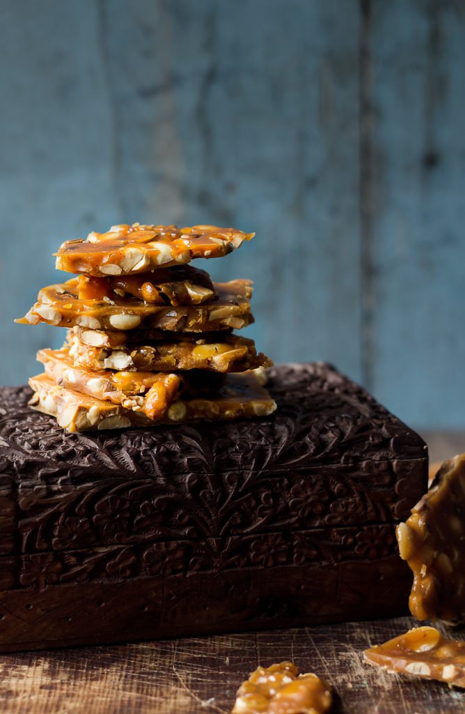 Close-up of golden brown peanut brittle pieces stacked on the box