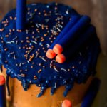 A vibrant and colorful Eggless Nerf Gun Cake decorated with colored chocolate drip