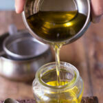 Freshly strained ghee, clear and golden, in a glass jar