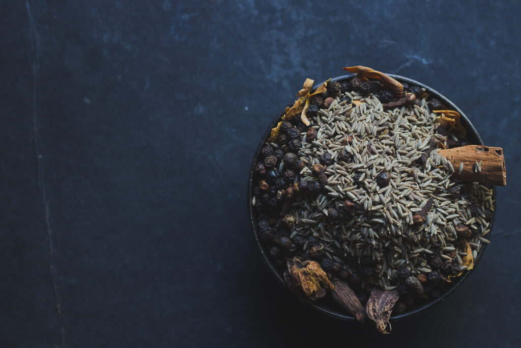 Spices being mixed together in a bowl to create a homemade garam masala blend