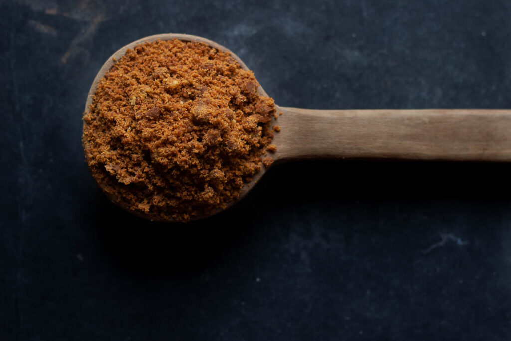 Close-up of a spoonful of Bura sugar, showcasing its natural texture
