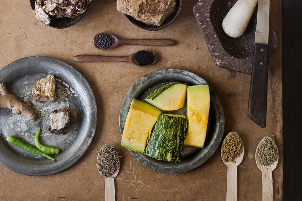 Khatta meetha kaddu in a bowl with spices and pumpkin chunks