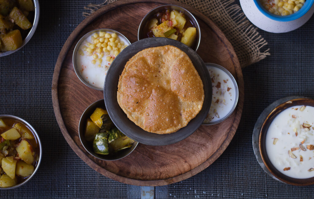 Golden, crispy Bedmi Puri served with spicy potato curry on a plate