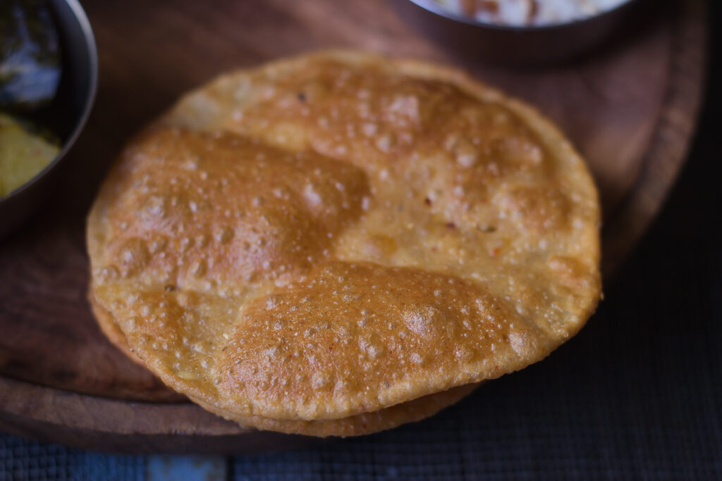 Freshly fried Bedmi Puri draining on a paper towel to remove excess oil