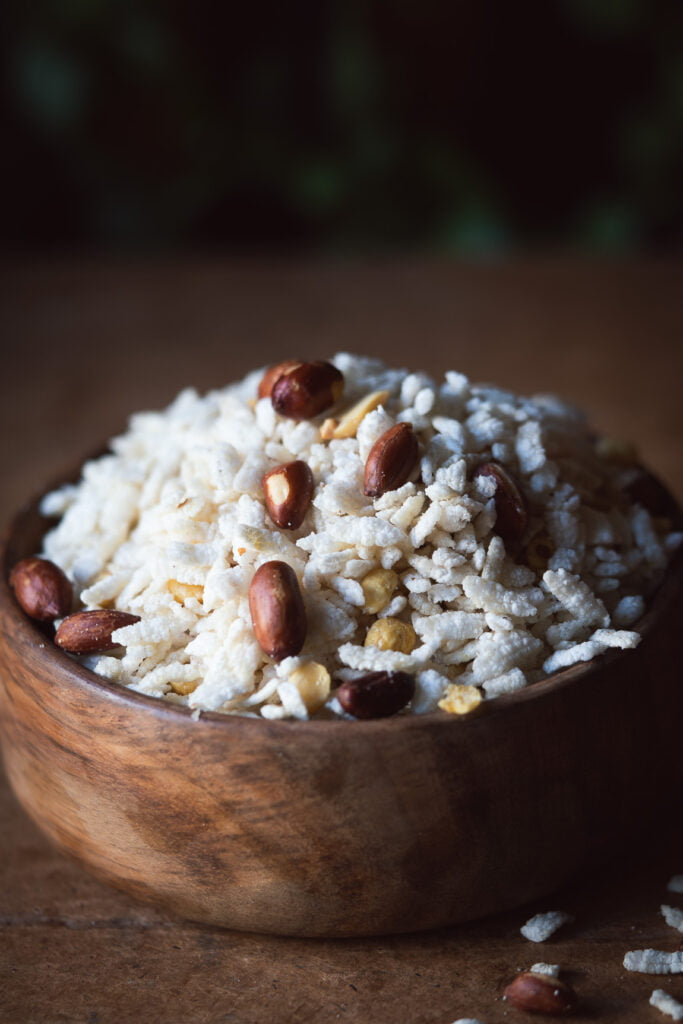 A bowl of freshly prepared Poha Chivda Namkeen garnished with curry leaves and peanuts, showcasing the vibrant colors and crispy texture