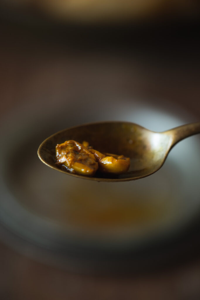 A spoonful of Karoda Pickle being scooped out of a jar