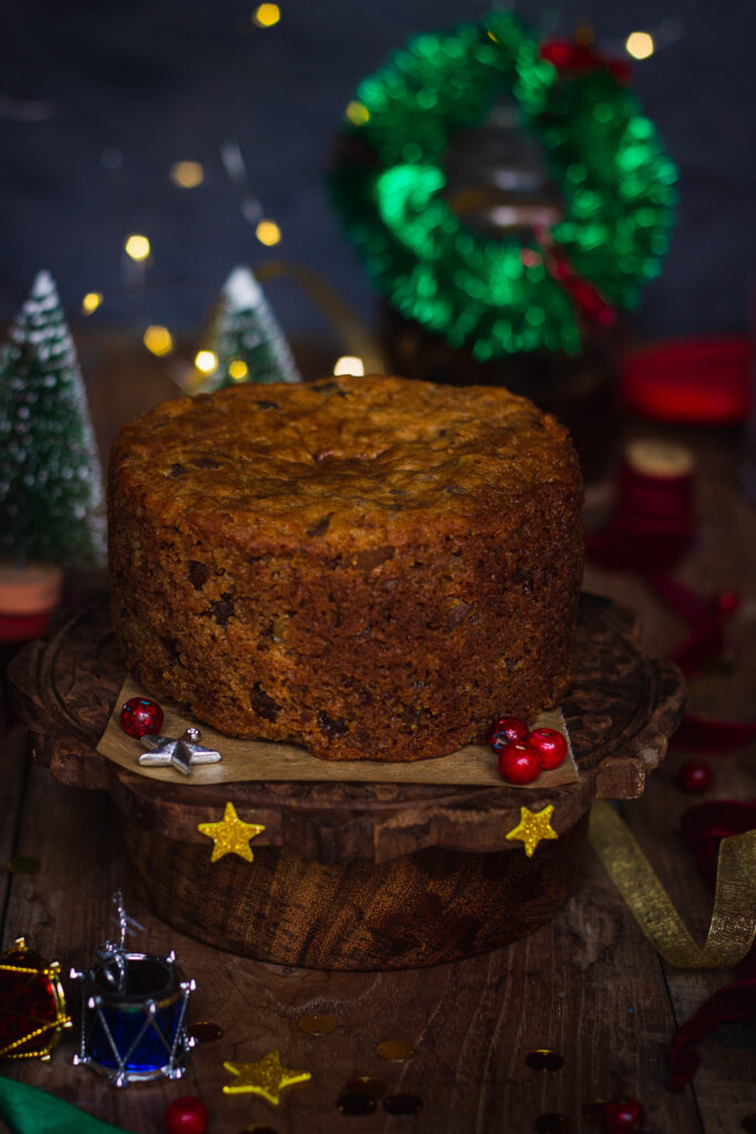 A festive table setup featuring a brandied fruit cake centerpiece and holiday props