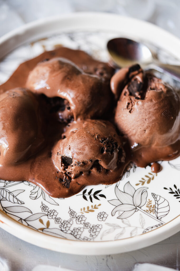 Scoops of chocolate ice cream garnished with chocolate sauce and nuts
