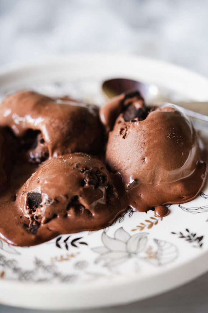 Homemade chocolate ice cream being scooped from a freezer-safe container