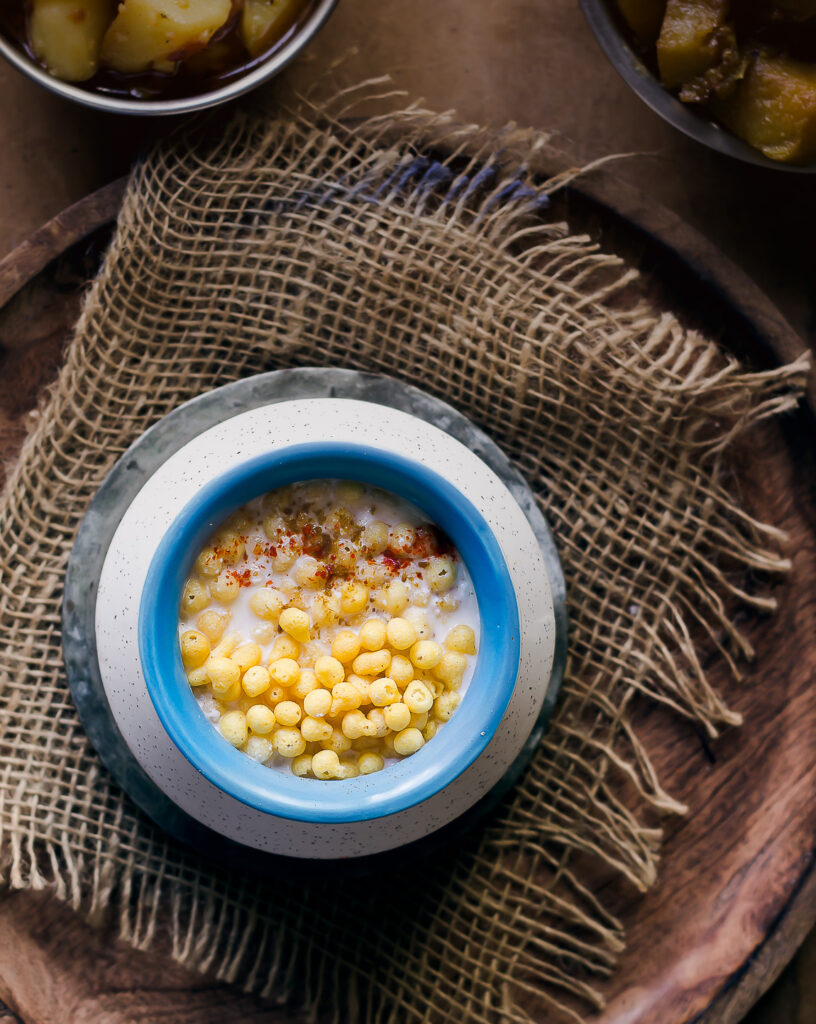 A bowl of boondi ka raita with a sprinkled red chilli powder on the top